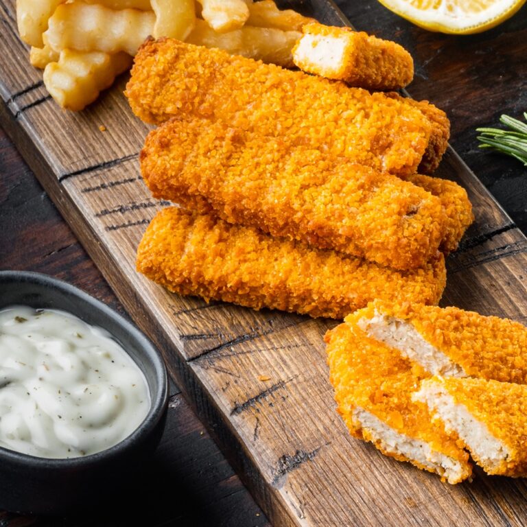 Fish Sticks with vegetables, on wooden cutting board, on old dark wooden table background , with copyspace and space for text